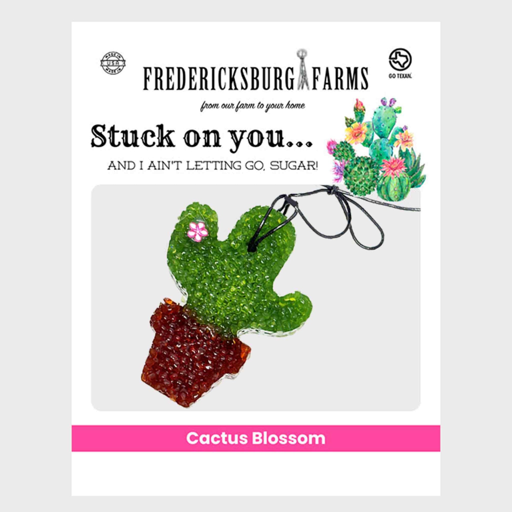 Fredericksburg Farms Cactus Blossom air freshener. The product is a glittery green cactus charm with a small pink flower and a brown pot, shown on a white product card with branding and illustrations.