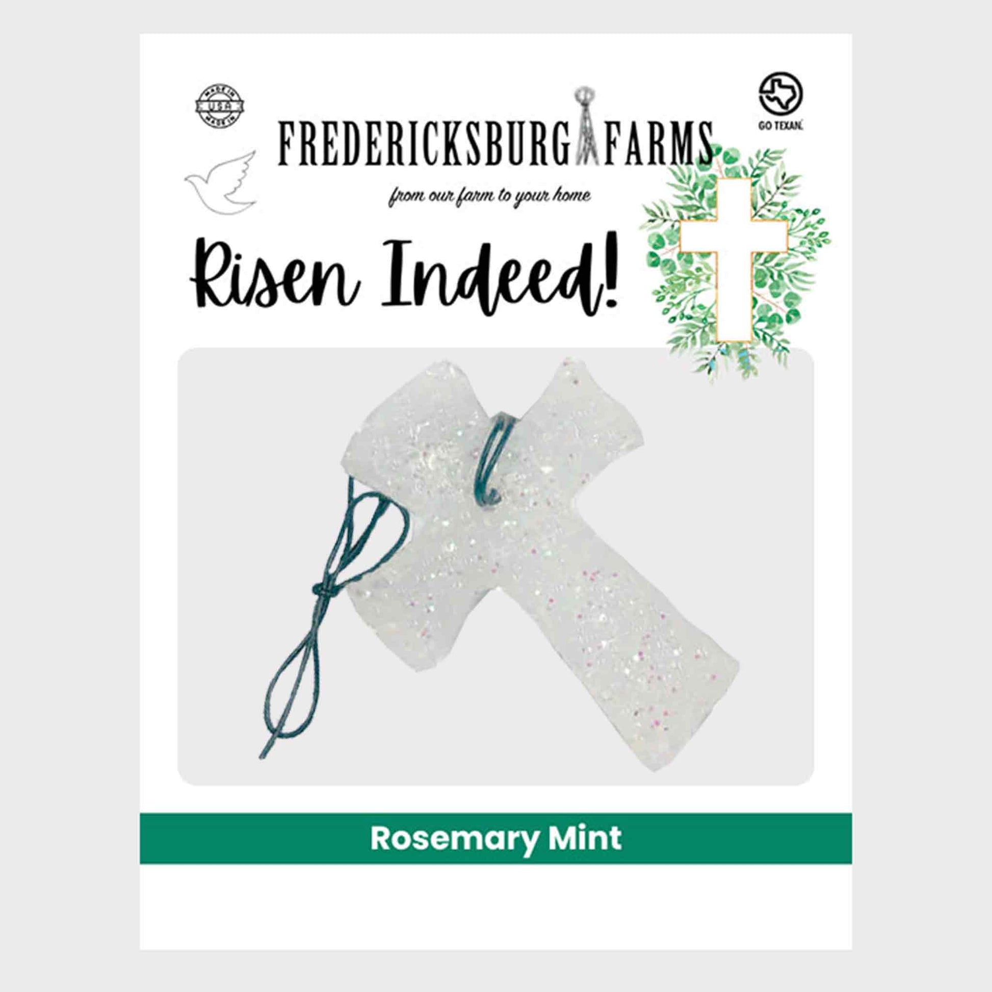 Fredericksburg Farms 'Risen Indeed!' rosemary mint scented candle packaging, featuring a clear glittery cross ornament with a dark green string on a white background.