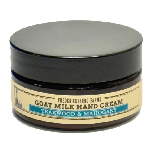 A jar of Fredericksburg Farms Goat Milk Hand Cream in the Teakwood & Mahogany scent, featuring a black lid and a beige label with a teal accent stripe.