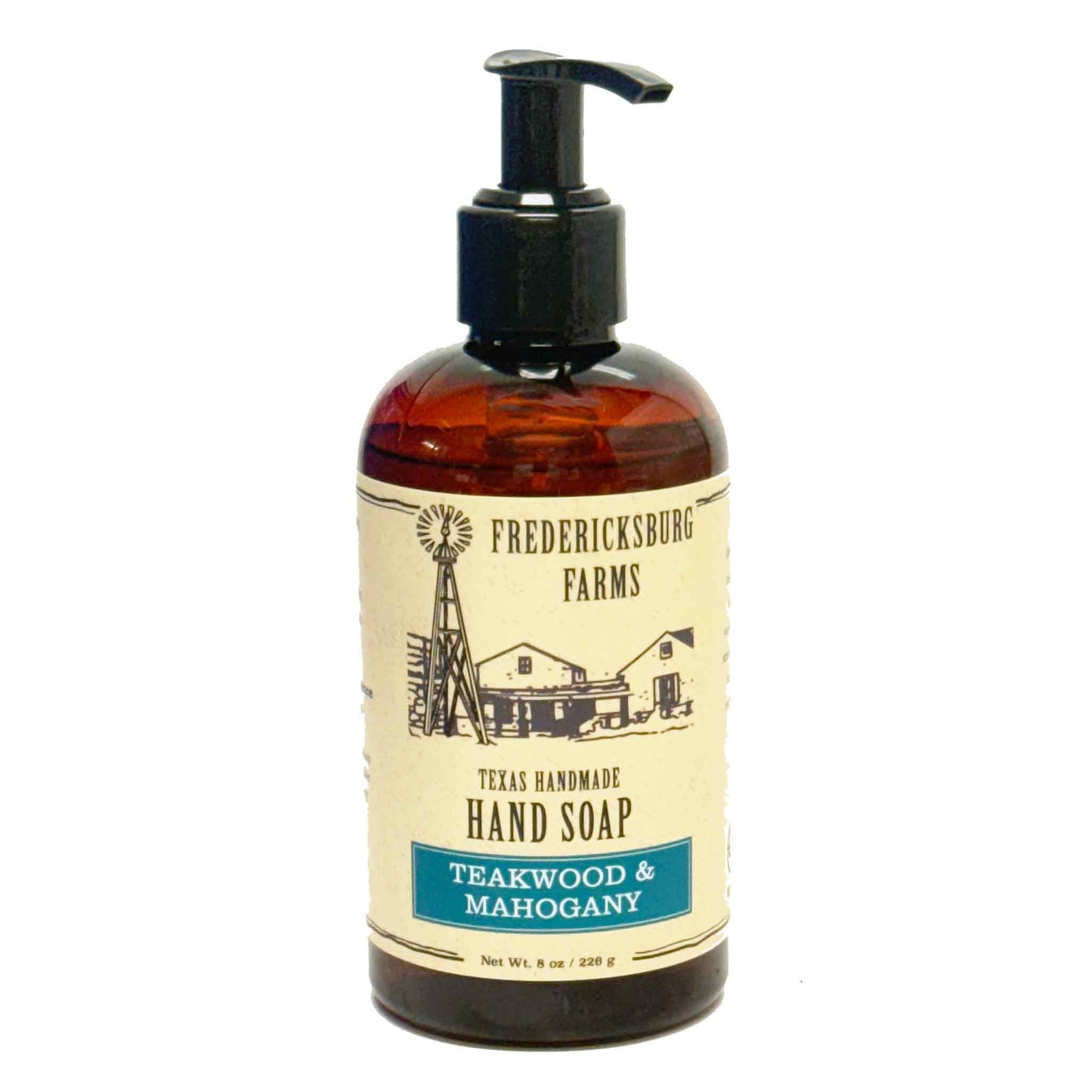 A bottle of Fredericksburg Farms Texas Handmade Soap, Teawood & Mahogany scent, in an amber glass bottle with a black pump dispenser and a cream-colored label.