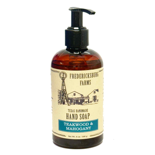A bottle of Fredericksburg Farms Texas Handmade Soap, Teawood & Mahogany scent, in an amber glass bottle with a black pump dispenser and a cream-colored label.